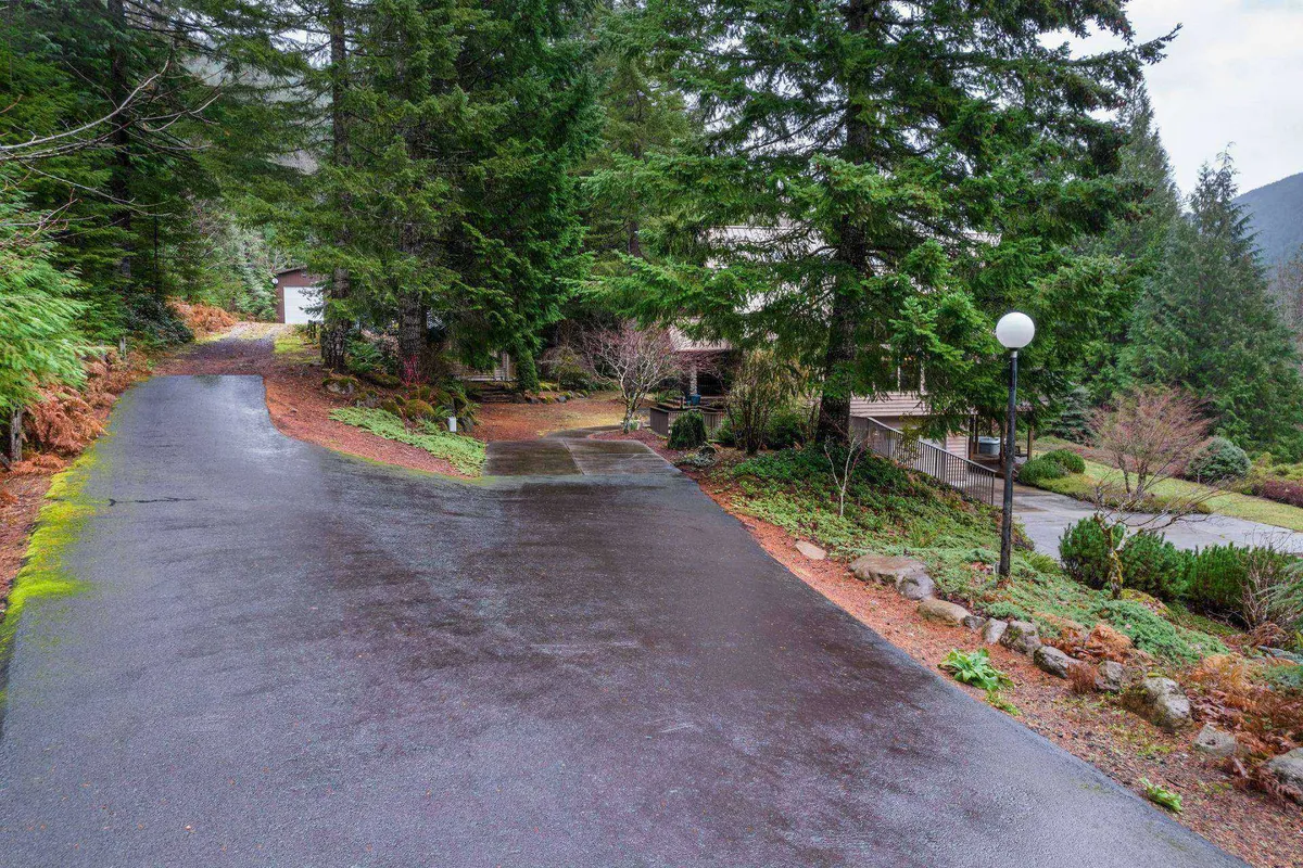 An exterior image featuring a winding driveway leading through the trees toward the house, with landscape lighting and a sense of peaceful seclusion. This scene evokes the journey of arrival and the anticipation of exploring the estate's natural surroundings.