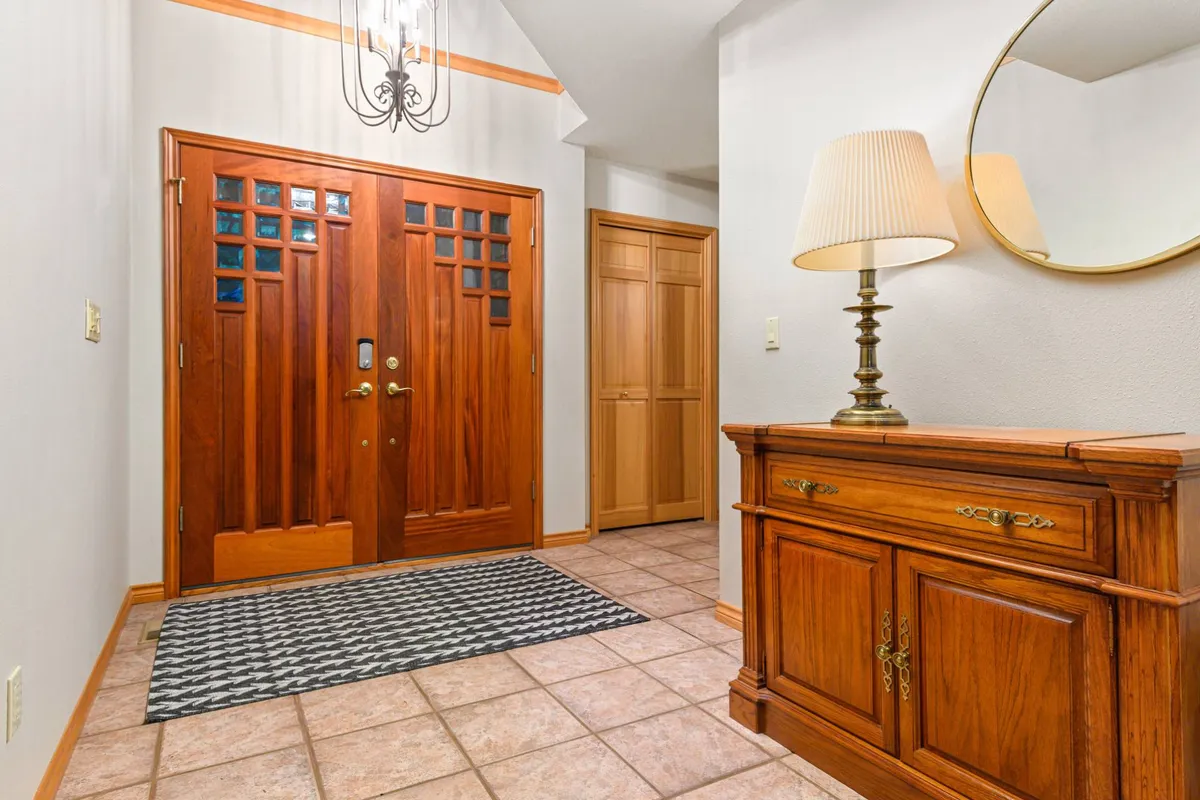 This image shows the wooden front door of Mountain View Retreat, accompanied by a console table, lamp, and mirror. Natural light streams in, creating an inviting and welcoming first impression. The view hints at the transition between the cozy interior and the great outdoors, suggesting the beginning of an adventure in every season.